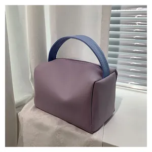 Detail of candy-colored lavender square handbag with a blue woven handle design