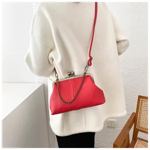 Detail of red shell bag with lychee texture and bronze chain on white coat