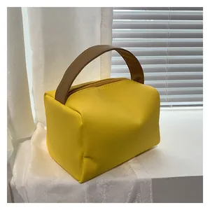 Detail of yellow faux leather square handbag with brown textured wood-grain handles