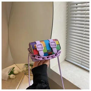 Detail of a mini rainbow checkerboard bag featuring dual purple buckled straps and a plastic chain