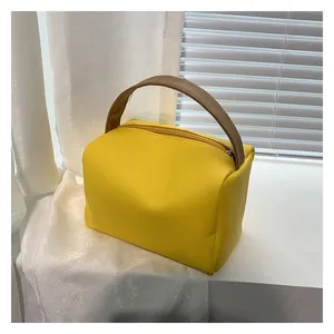 Detail of a bright yellow PU leather handbag featuring a contrasting brown leather handle