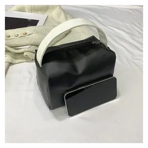 Detail shot of a small black cosmetic bag next to a smartphone showing compact size