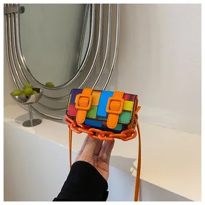 Detail of mini crossbody bag featuring mosaic color block design and orange chain strap