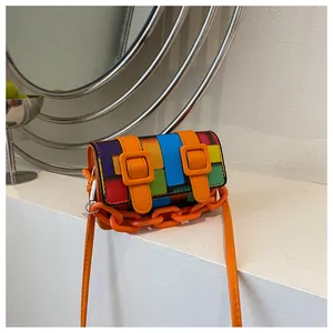 Detail of colorful mosaic pattern crossbody bag with orange chain and bold square buckles