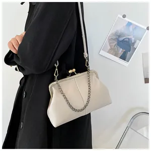 Detailed view of cream lychee texture shell bag with brass clasp worn by a model