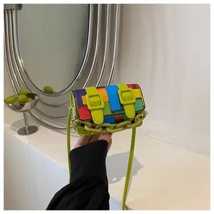 Detail of color-block crossbody bag with neon straps and stylish plastic chain
