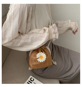 Detail of woven straw bucket bag with knitted daisy flower and thick white rope drawstring
