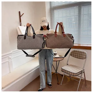 Dettaglio di una borsa da viaggio pied-de-poule con doppi manici e finiture in pelle