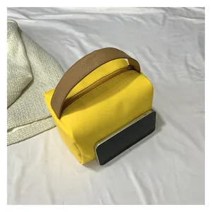 Bright yellow handbag with dark brown handles and smartphone for size reference