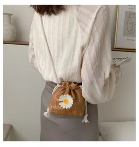 Detailed view of handwoven straw bucket bag with white daisy flower appliques and drawstring