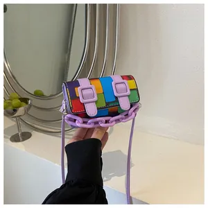 Detail of colorful mosaic patchwork handbag with purple chain and belt buckle decorations
