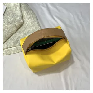 Macro shot of yellow PU leather cosmetic bag with brown textured handle and metal zipper