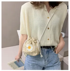 Close-up of a straw bucket bag with drawstring closure and white daisy flower pattern