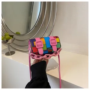 Detail of a mini mosaic crossbody bag featuring colorful patchwork and a pink chain handle
