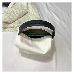 Detail of bicolored mini bag with woven handle and interior storage for a smartphone