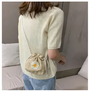 Straw drawstring bucket bag with daisy detail shown on model in a casual outfit