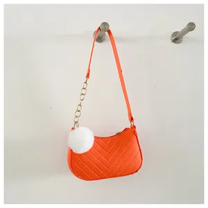 Detail van levendige oranje gewatteerde tas met gouden ketting en pomponhanger