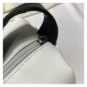 Close-up of black braided handle and zipper on a white leather handbag detail