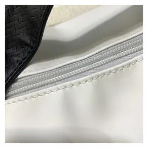 Detail view of smooth white leather texture with neat stitching and zipper on handbag