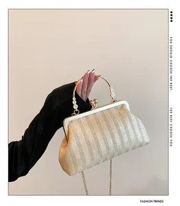 Détail d'un sac à main beige en paille tressée avec anse dorée à motifs floraux