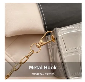 Detailed close-up of premium gold hardware hook and metallic crocodile texture on small bag