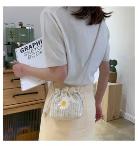 Detailed view of cream straw bucket bag with daisy ornament shown in lifestyle setting