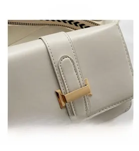 Détail du sac en cuir crème avec boucle dorée et bandoulière tissée géométrique