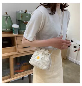 Detail of white woven straw bucket bag with daisy embroidery and drawstring closure