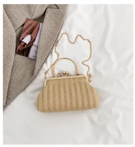 Détail du sac en paille tressée beige avec fermoir métallique et bandoulière chaîne