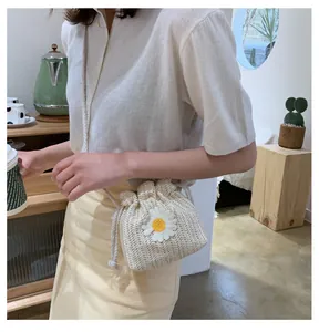 Detail of hand-woven straw bucket bag with daisy flower decor on a model's shoulder