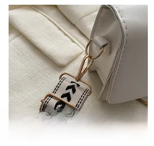 Détail du sac en cuir blanc montrant le crochet doré et la large bandoulière tissée