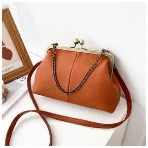 Detail of orange lychee leather shell bag with vintage metal clasp and chain strap
