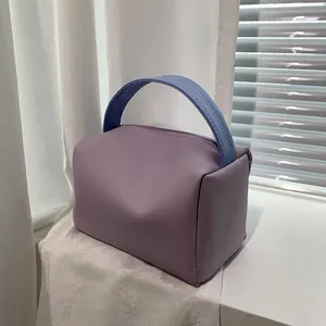 Minimalist light purple leather handbag with blue woven textured handles and zip closure