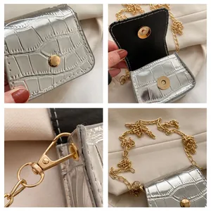Detail view of silver crocodile pattern mini square bag with gold chain strap details