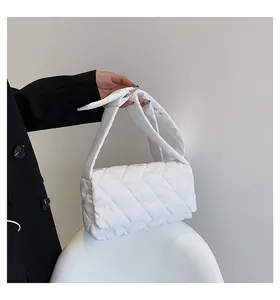 Gros plan d'un sac matelassé blanc avec motif à losanges et bandoulière réglable