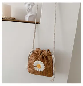 Macro detail of the dark brown straw weave bucket bag featuring a white daisy embroidery