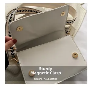 Détail d'un sac à bandoulière blanc montrant les boucles magnétiques en métal doré