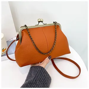 Close-up of litchi texture orange shell bag with vintage metal kiss-lock and chain
