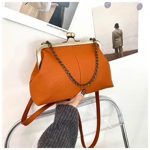 Detail of vintage orange shell bag with kiss-lock closure and lychee grain leather texture
