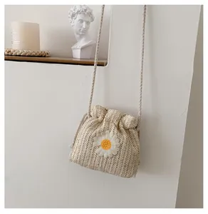 Detail of hand-woven straw bucket bag with floral daisy embroidery and drawstring closure