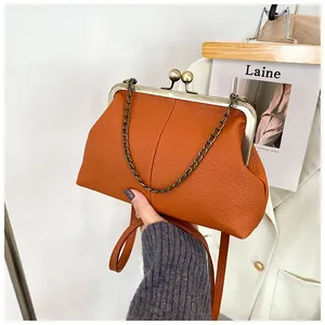 Detailed close-up of caramel lychee pattern leather shell bag with metal clasp and chain