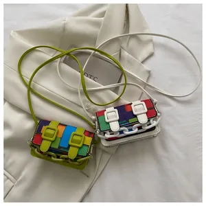 Close-up of mini color-block crossbody bags with plastic chains on white fabric
