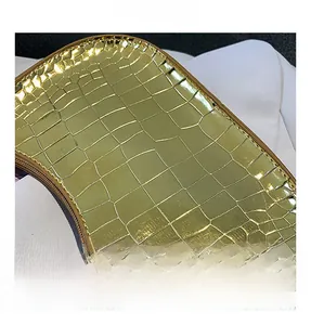 Close-up of golden crocodile pattern leather and metallic zipper detail on the shoulder bag