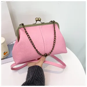 Detail showing the pink litchi grain leather and retro metal clasp of the handbag