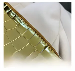 Close-up of golden crocodile texture material with precise stitching on a fashion handbag