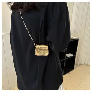 Detail of a mini gold crocodile pattern chain bag showing metallic shine and texture