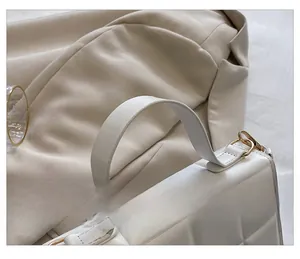 Gros plan détaillé sur la texture en cuir blanc matelassé et l'anse robuste du sac à main