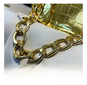 Close-up of gold metal chain and gold crocodile texture leather on a stylish square bag