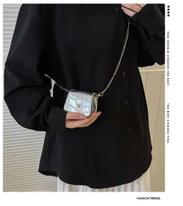 Detail of mini silver crocodile pattern handbag with gold chain on black shirt