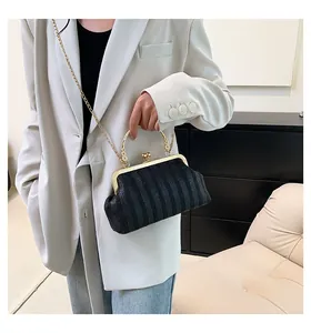 Détail du sac coquille vintage noir avec poignée fleurie dorée et texture tissée